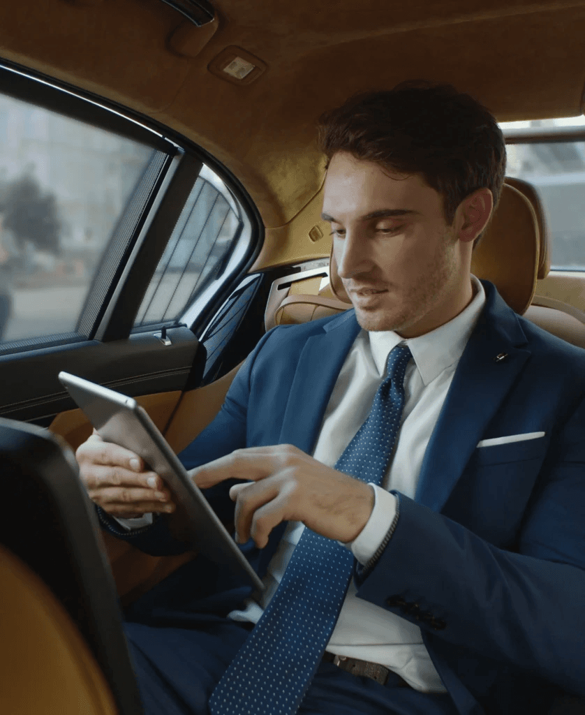 Business executive in suit reviewing documents while being chauffeured in luxury vehicle
